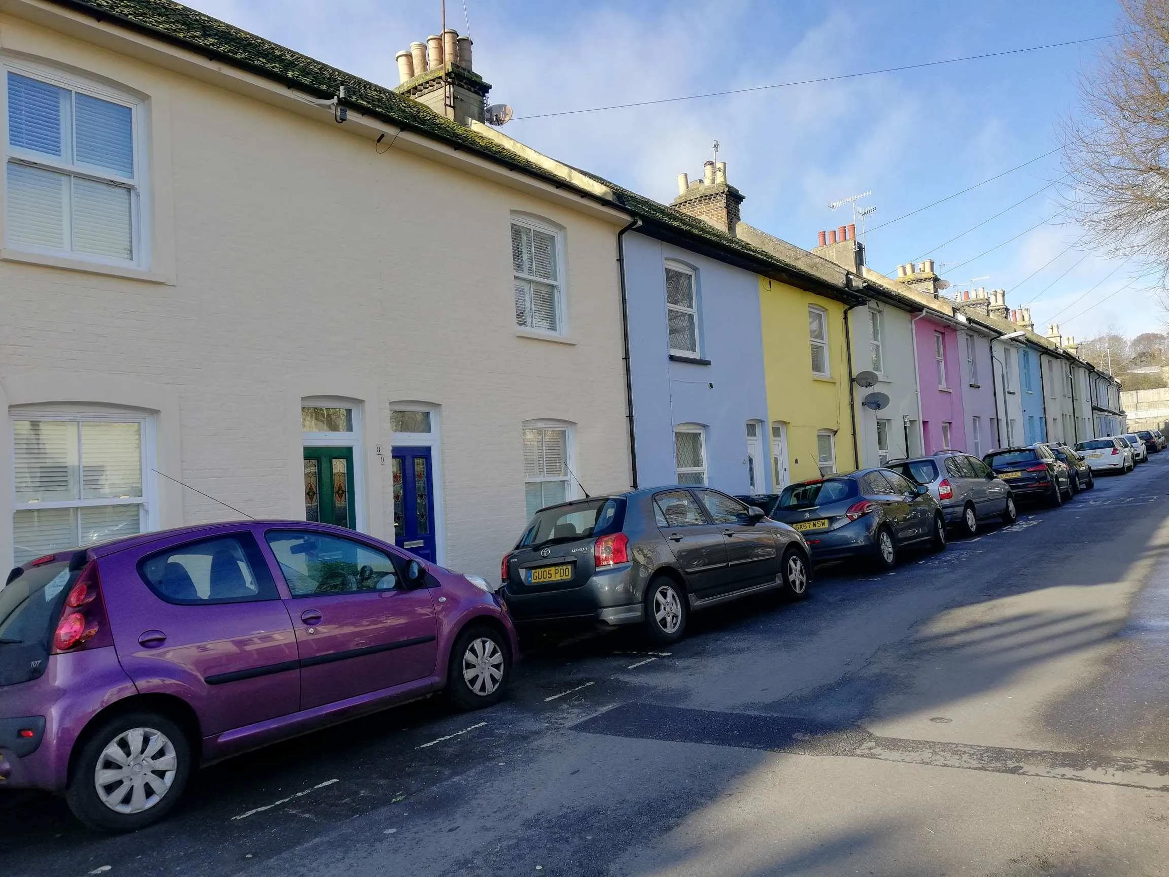 Colorful terraced houses in Brighton UK with parked cars along residential street near Loxdale English Centre