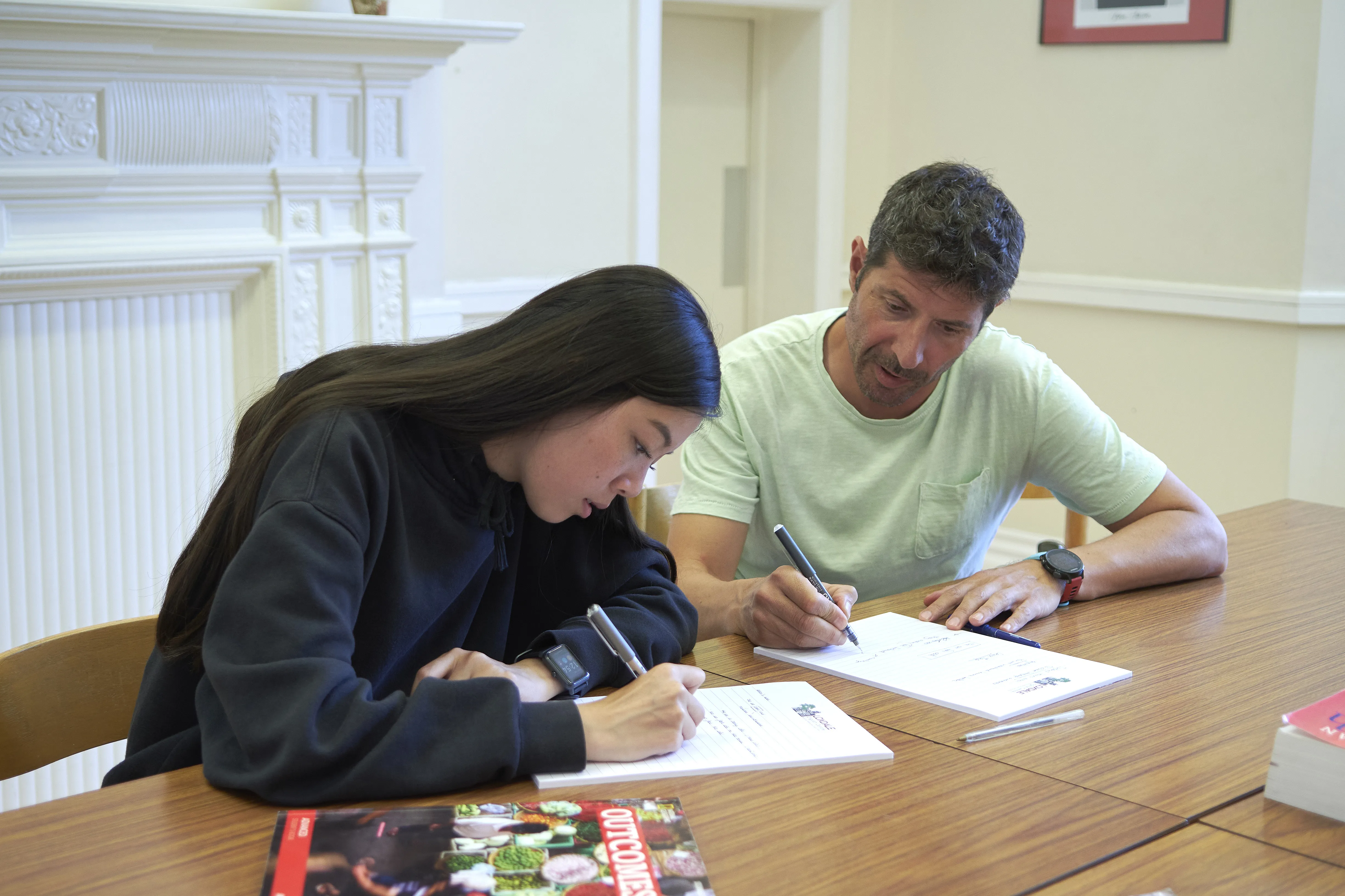 Two students writing in small-group English lesson at Loxdale English Centre Brighton classroom