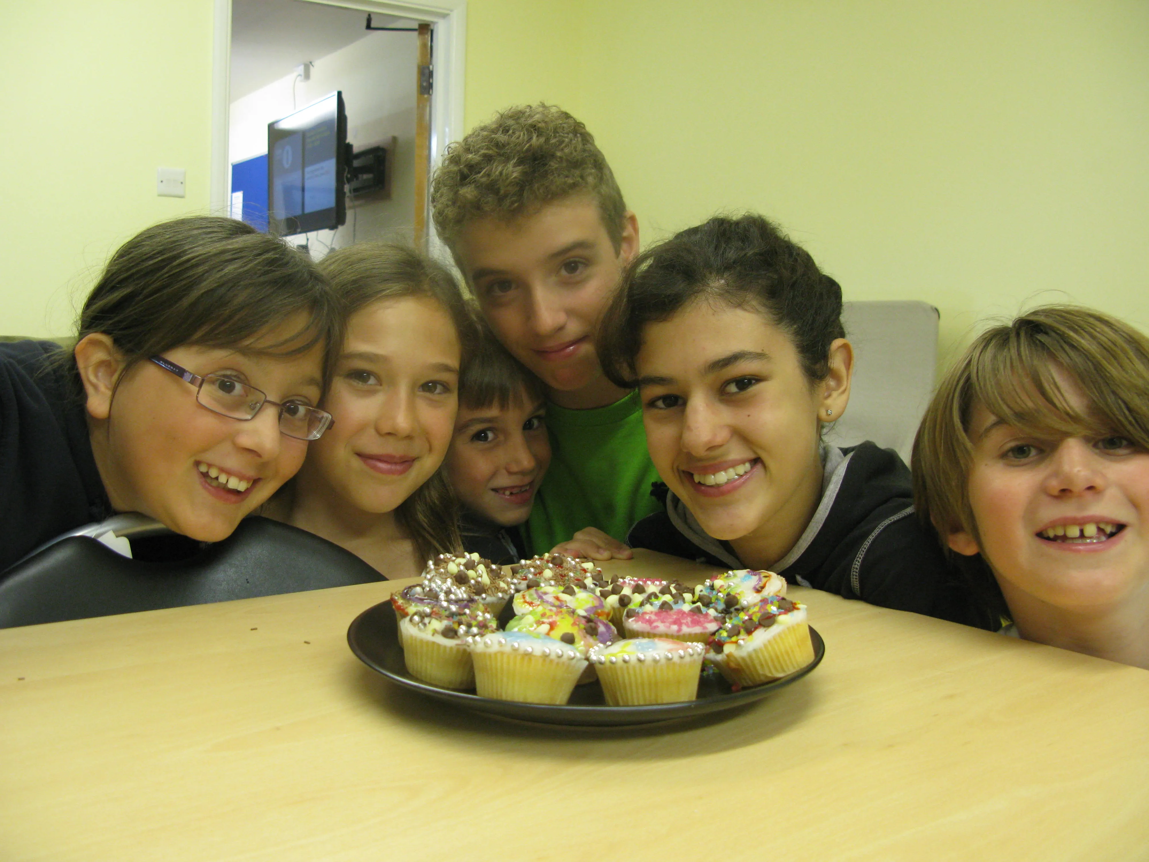 Six happy students gathered around decorated cupcakes at Loxdale evening event