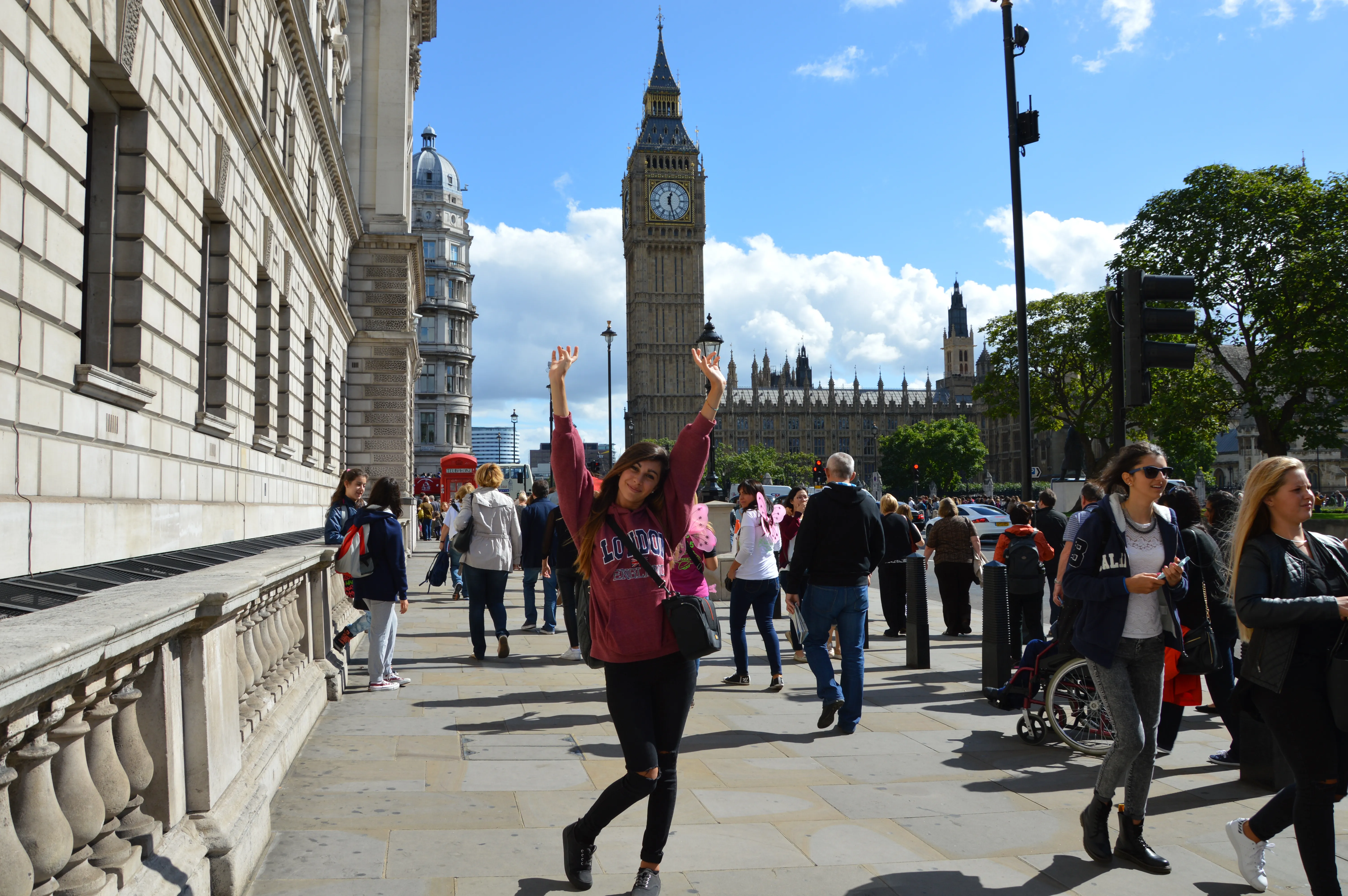 Happy Loxdale English Centre student with arms raised celebrating in front of Big Ben and Westminster during London trip