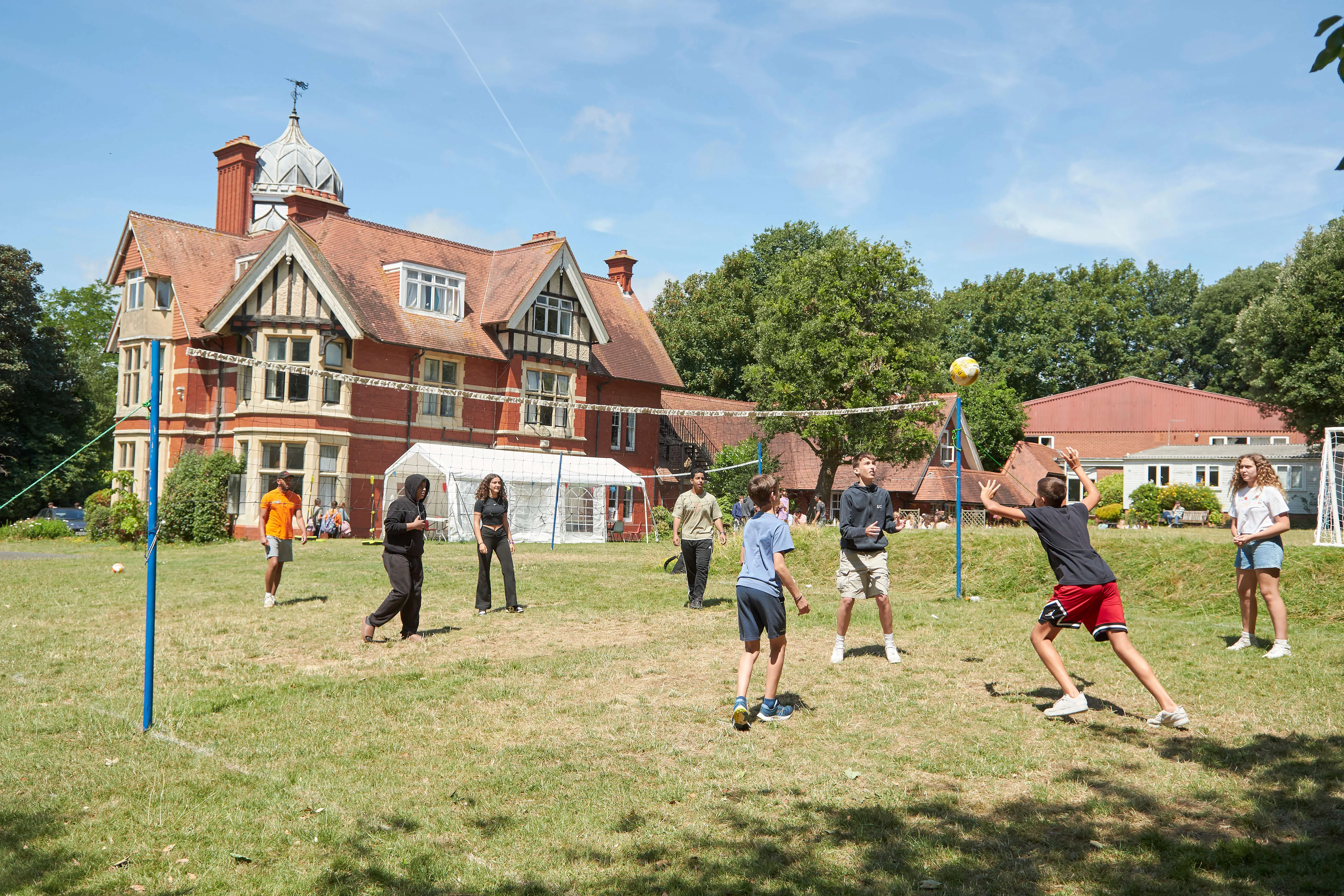 Students playing volleyball on grass field at Loxdale English Centre Brighton