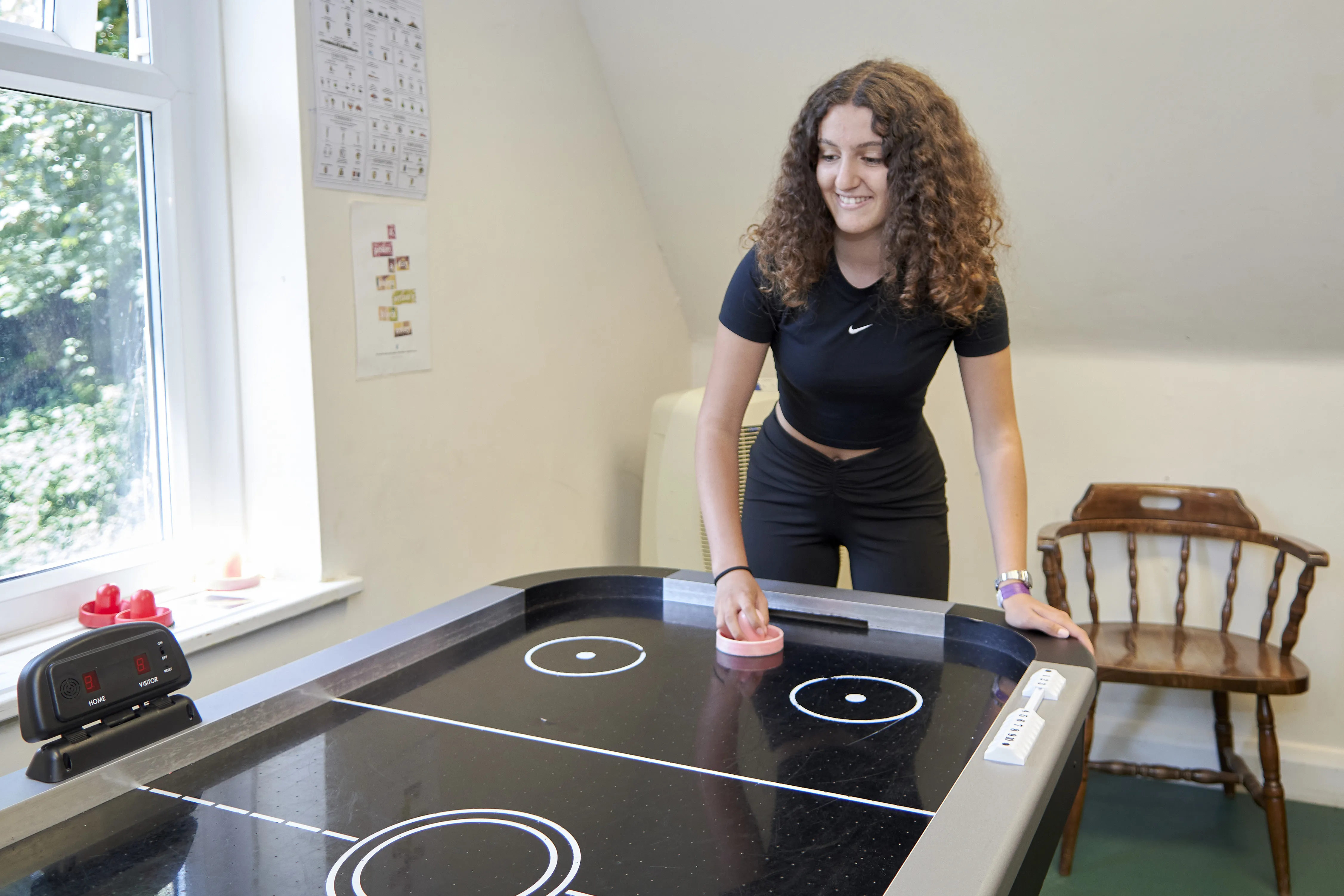 Female student enjoying air hockey game in modern student common room at Loxdale English Centre Brighton