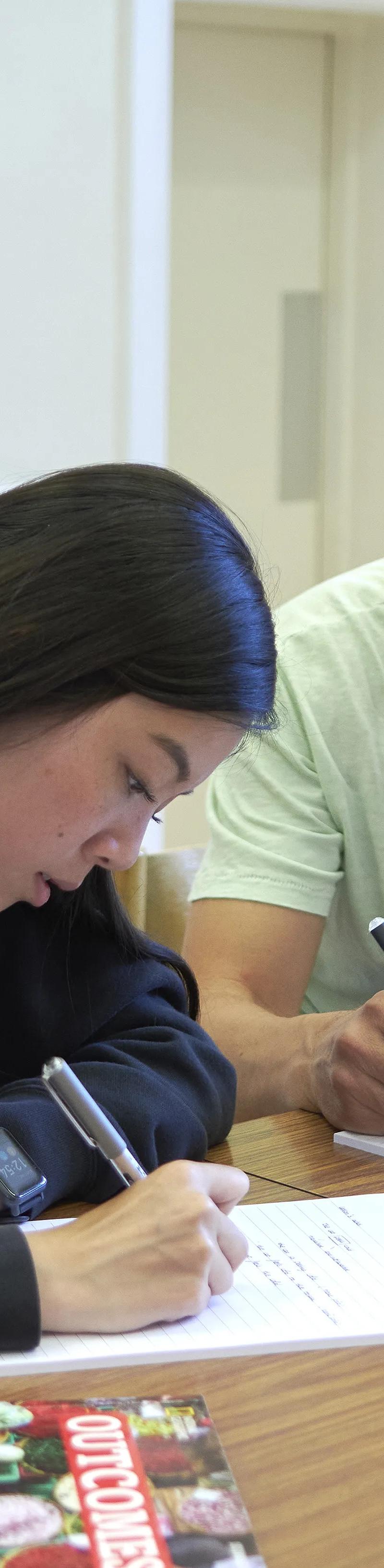 Two students writing in small-group English lesson at Loxdale English Centre Brighton classroom
