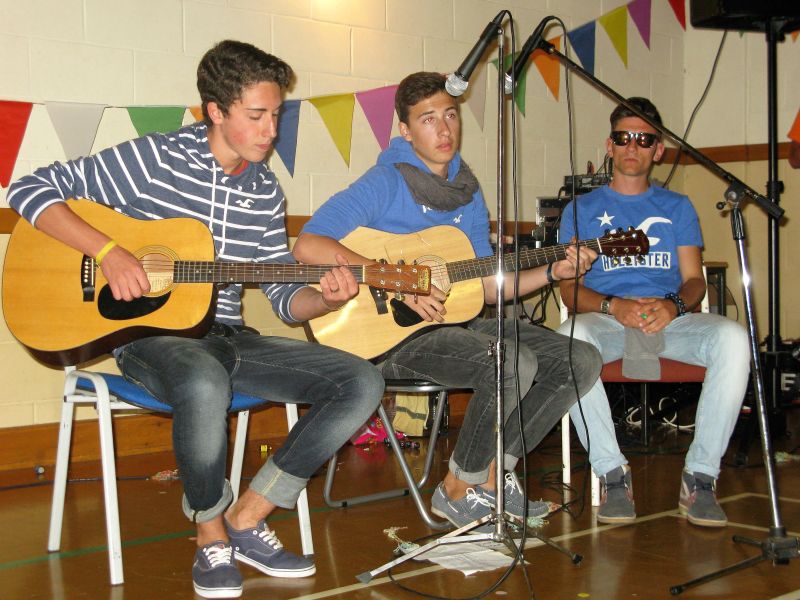 Three young men performing acoustic music at Loxdale English Centre Brighton social activity event
