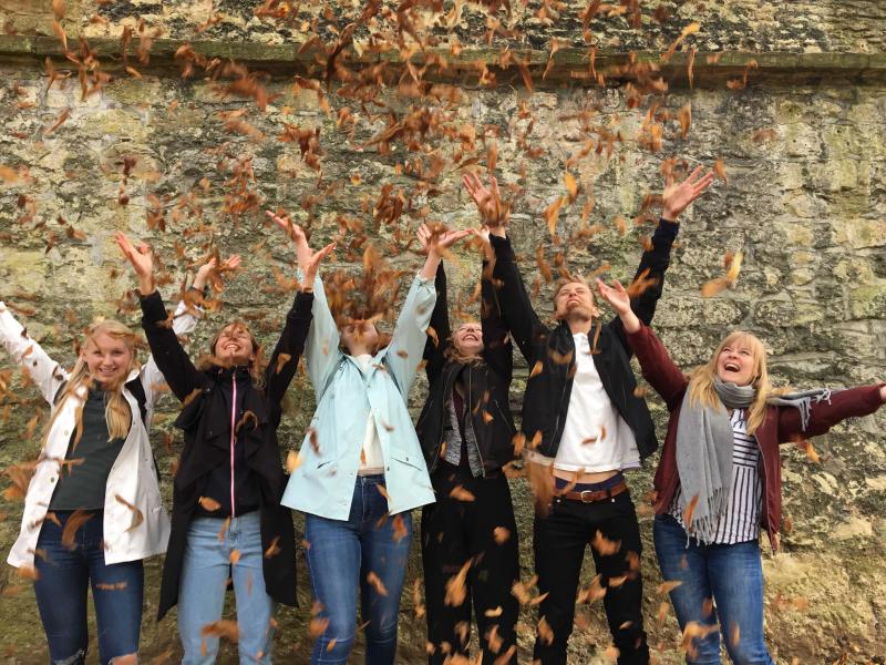 Happy international students throwing autumn leaves in the air at Loxdale English Centre Brighton